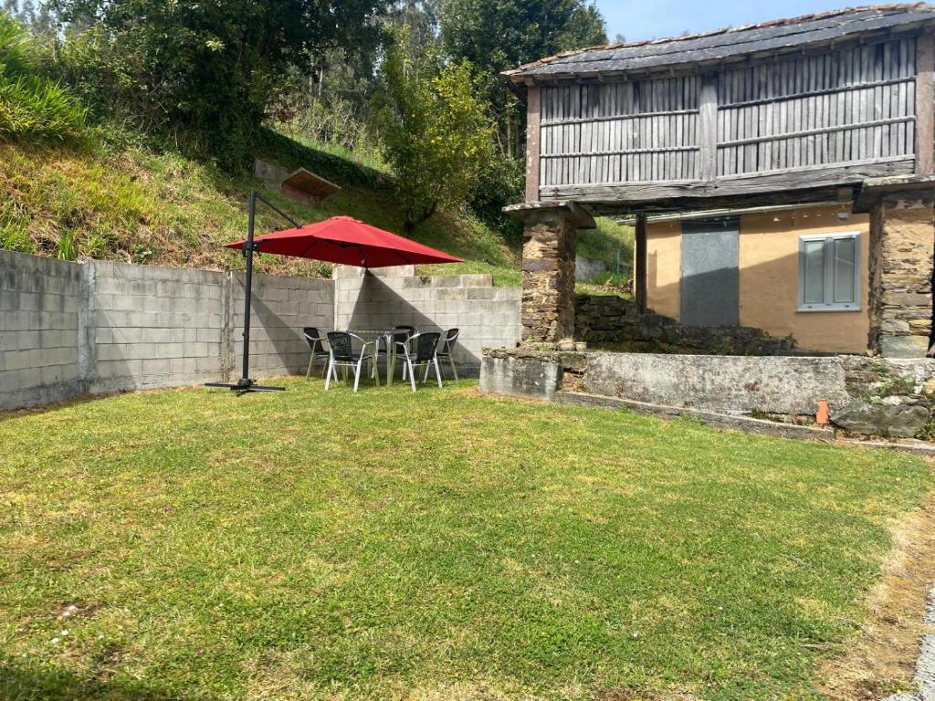 a patio with a red umbrella and chairs in a yard at Casa Lameiro in Cedeira