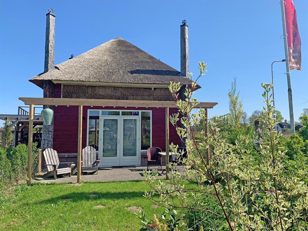 a small red house with two chairs in a yard at B&B De Rooie Hooimijt in Ammerzoden