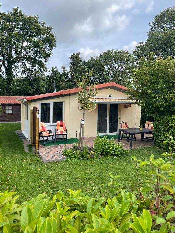 a house with a table and chairs in a yard at Zonneschijn, bungalow op vakantiepark bij zee in Baarland