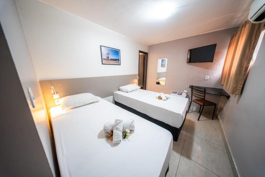 a hotel room with two beds and a desk at Hotel Montana Aeroporto by Bsb Inn in Brasília