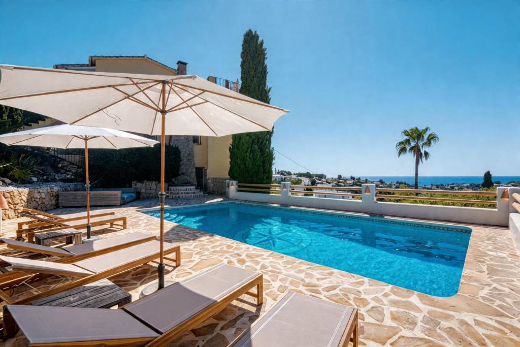 a swimming pool with two chairs and an umbrella at Robis Moraira in Benissa