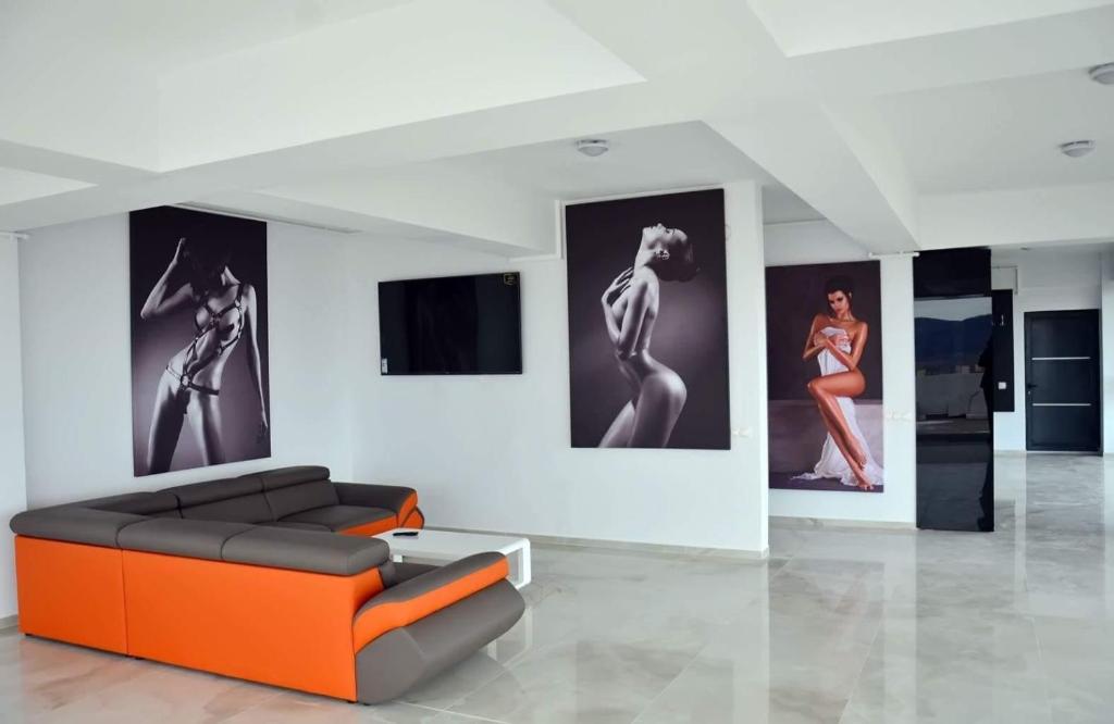 a living room with an orange couch and pictures on the wall at Rania Penthouse 1 in Şelimbăr