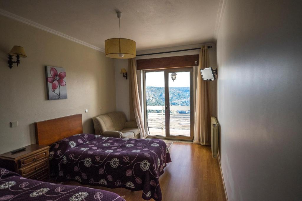 a hotel room with two beds and a window at Flor Do Douro in Miranda do Douro