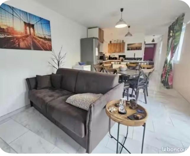 a living room with a couch and a table at Petit gîte a côté des plages in Triaize