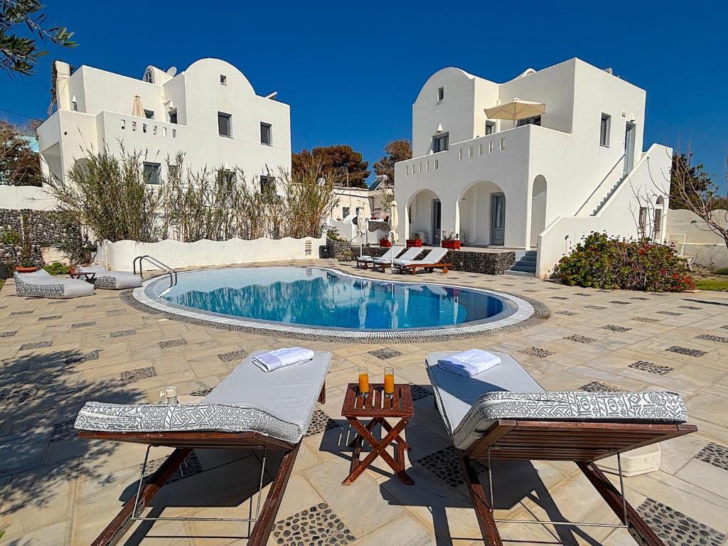 a patio with chairs and a pool in front of a building at Villa Galathea in Kamari