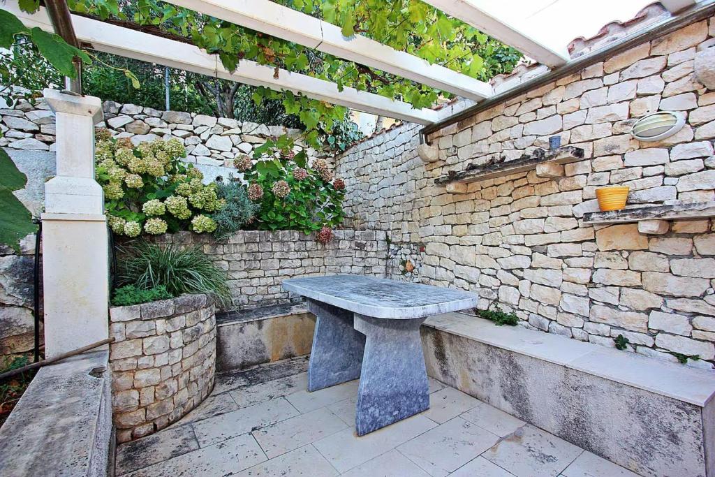 a stone patio with a stone bench in a brick wall at House Postira Horizon in Postira