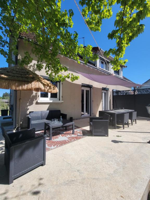 a patio with tables and chairs in front of a house at Gite piscine privée climatisation in Célon