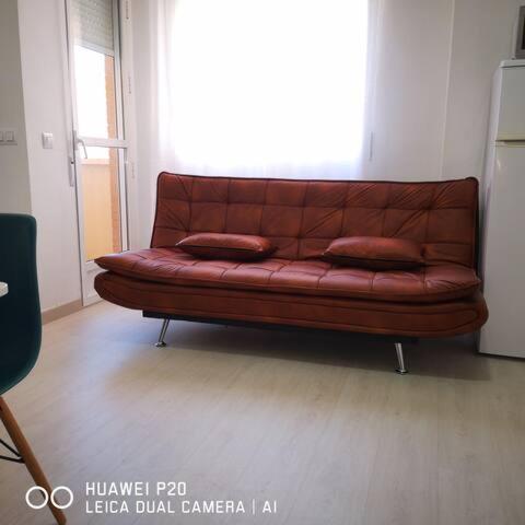 a brown leather couch in a room with a window at Aprt ESTUDIO ARRIXACA in Murcia