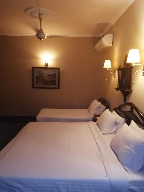 a bedroom with two beds and two lamps on the wall at Hotel Grand Peshawar in Peshawar