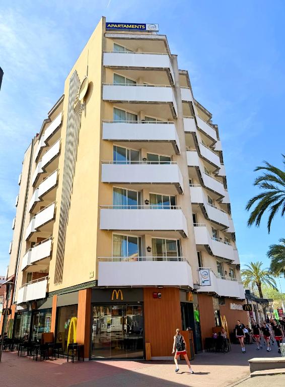 a tall building with a woman walking in front of it at Apartments Lloret Sun in Lloret de Mar