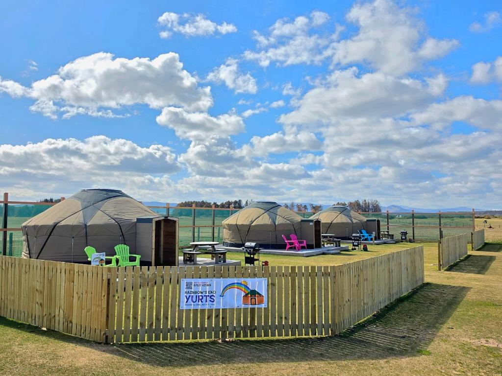 a group of domes with tables and chairs in a field at Rainbow's End Yurts in Dornoch
