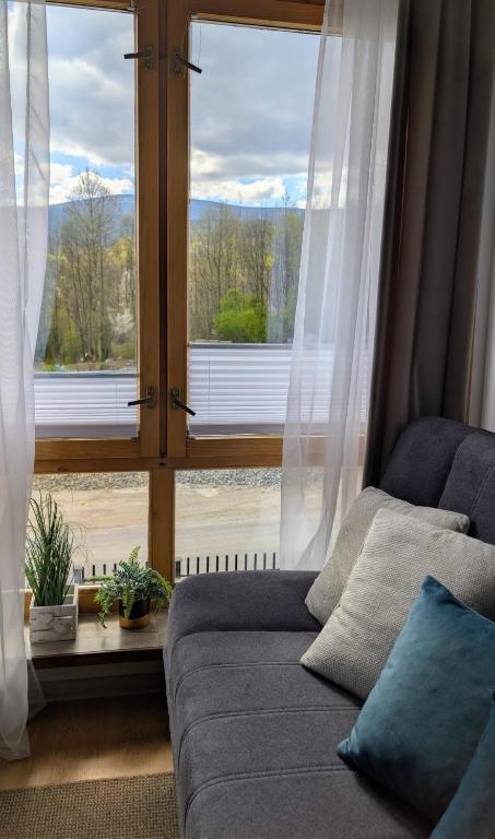 a living room with a couch and a large window at Domek za rzeką in Zawoja