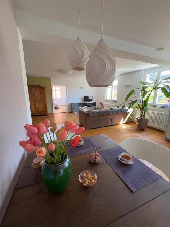 a living room with a table with a vase of flowers at Maison Bleue Dreiländereck, Design Apartment mit Terrasse in historischem Landhaus nahe Basel in Kandern