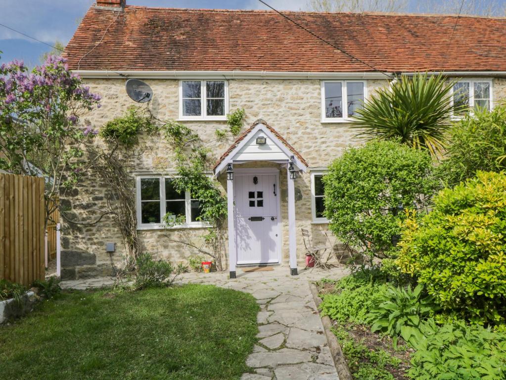 a stone house with a white door and a yard at Lavender Cottage in Gillingham