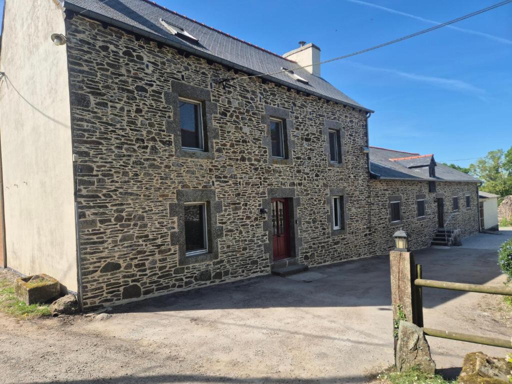 an old stone building with a red door at Les Gites Audrain in Plussulien