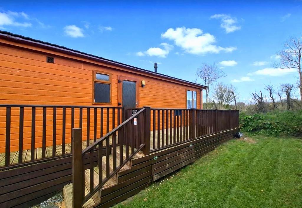 a house with a wooden fence in front of it at Bella Mere Lodge in West Down