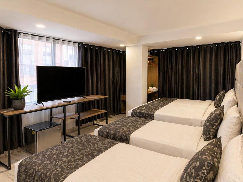 a hotel room with two beds and a flat screen tv at Aw Hotel Embassy Corner - Corferias, Embajada EEUU & Vive Claro in Bogotá