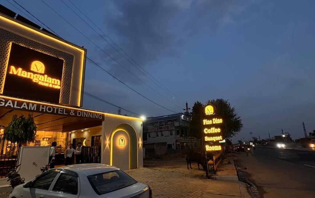 a car parked in front of a building with a sign at Mangalam Hotel and Restaurant in Lachhmangarh Sīkar