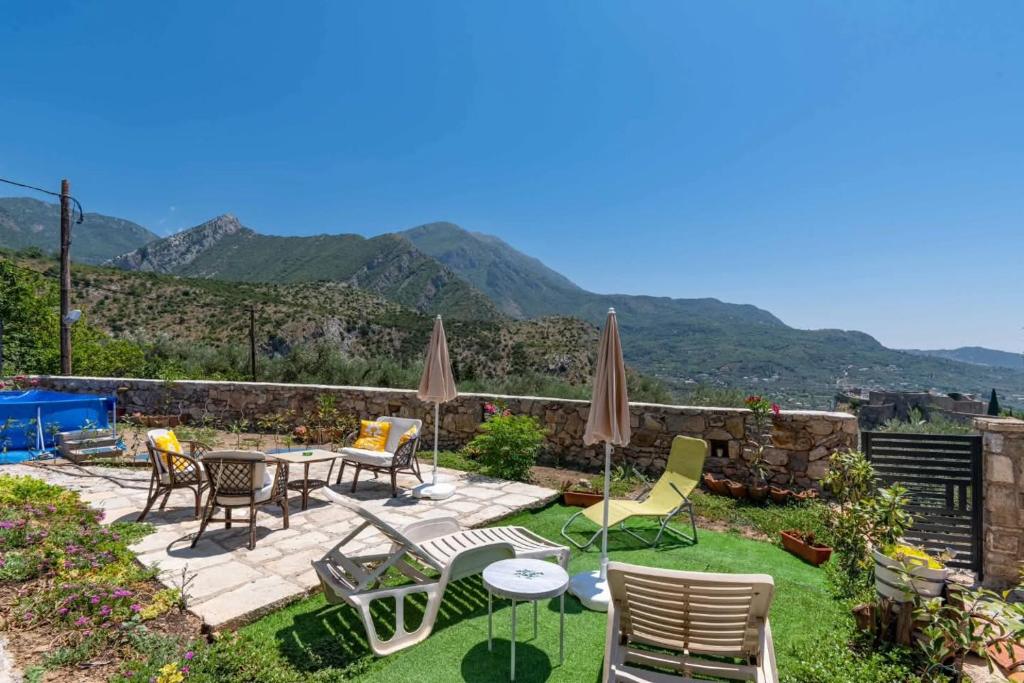 a patio with chairs and tables with mountains in the background at Apartmani Olga in Stari Bar