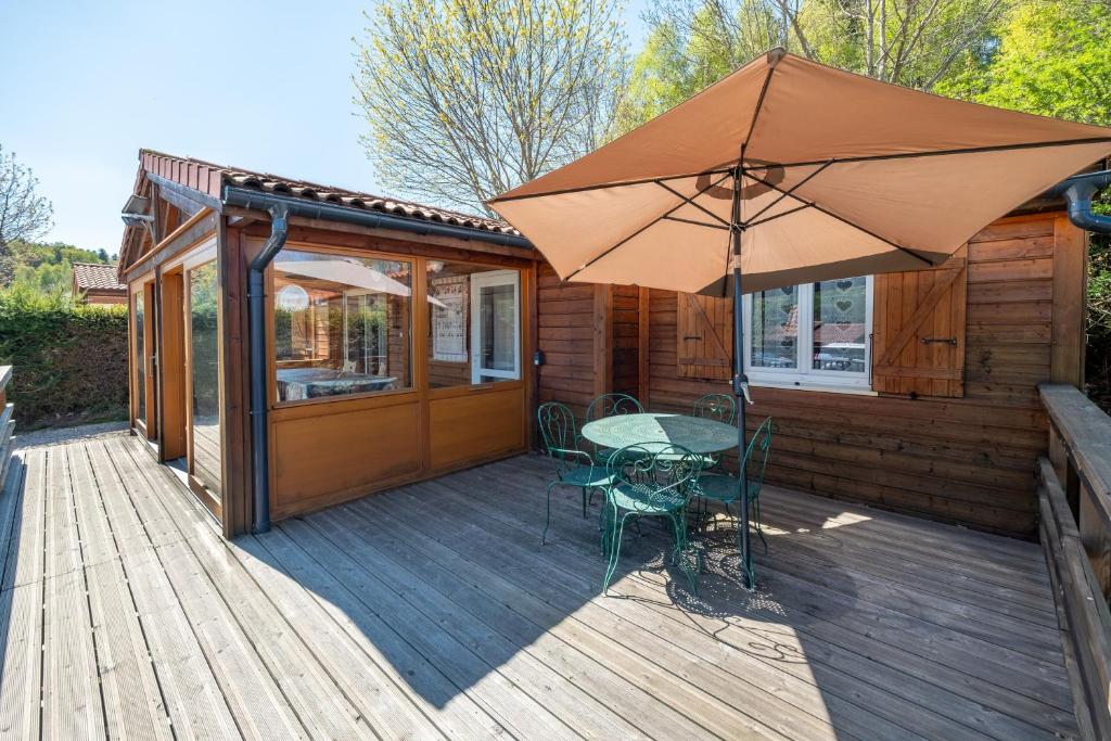 a wooden deck with a table and an umbrella at Chalet Le Sotré in Corcieux