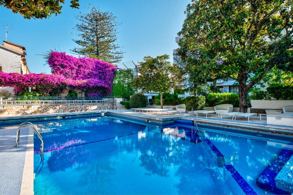 a swimming pool in a yard with trees and flowers at Majestic Palace Hotel in Sant'Agnello