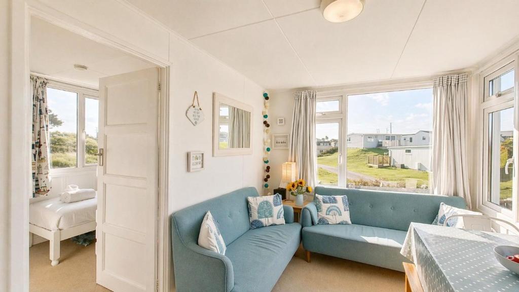 a living room with a blue couch and windows at F71 Elova, Riviere Towans in Hayle