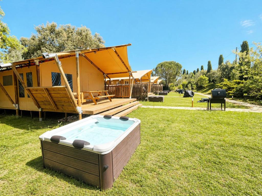 a hot tub in the grass in front of a house at Glamping Il Poderino in Cecina