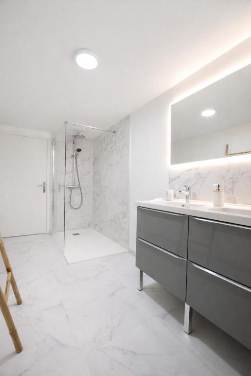 a white bathroom with a sink and a shower at Maison 10 personnes 4 chambre 2 sdb in Liourdres