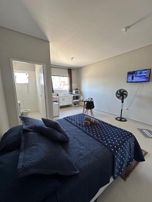 a bedroom with a blue bed and a television at 04 Studios centro,proximo a rodoviaria-itapeva sp in Itapeva