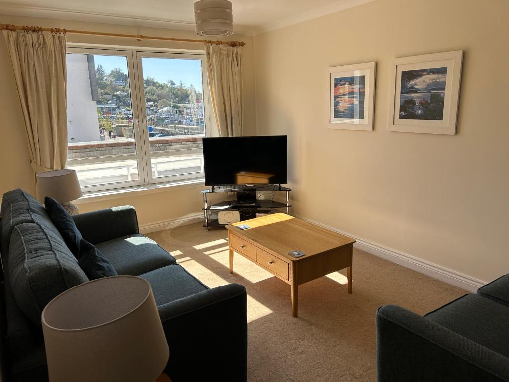 a living room with a couch and a tv and a table at 1/5 Lismore House in Oban