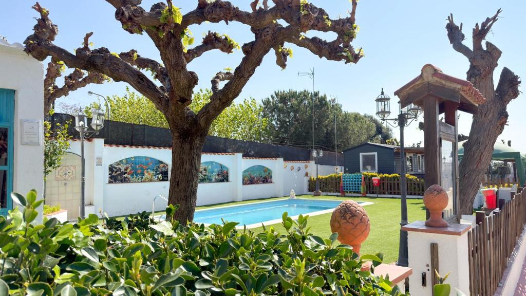 a pool in a yard with a tree and a fence at Camping Costa Dorada Bungalow Maia in Canet de Mar