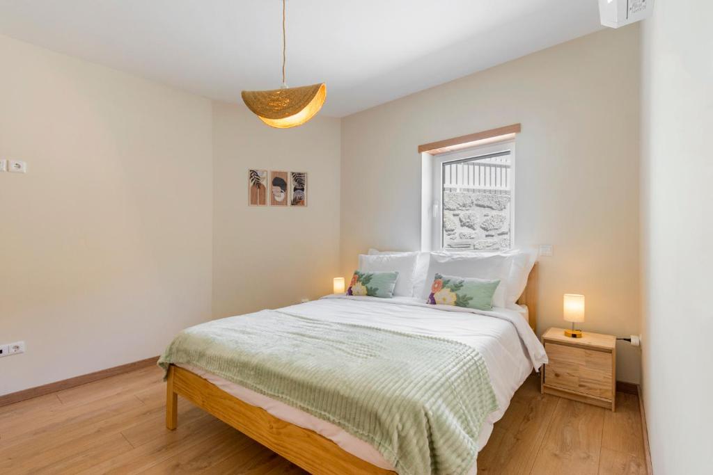 a white bedroom with a bed and a window at StoneBridge Riverside Mountain Apartments in Loriga