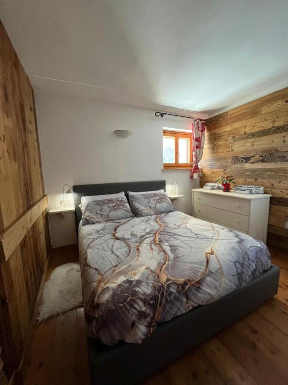 a bedroom with a bed and a wooden wall at Casa Lazer in Tonadico