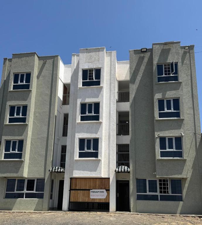 two tall apartment buildings in front of a blue sky at Miriam Inn, Chaka in Nyeri