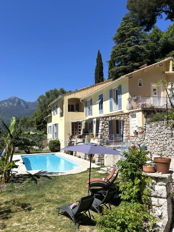 a house with a swimming pool and two chairs and an umbrella at Des Ciappes et des Fées in Menton