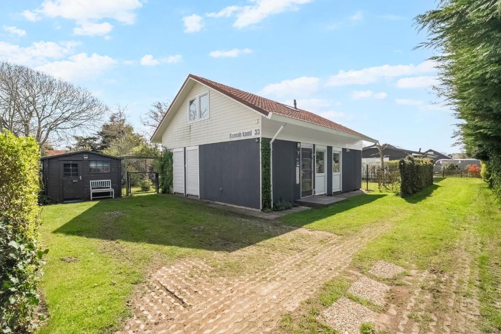 a small white house with a yard at Vakantiehuis Rumah Kami - Julianadorp aan Zee in Julianadorp