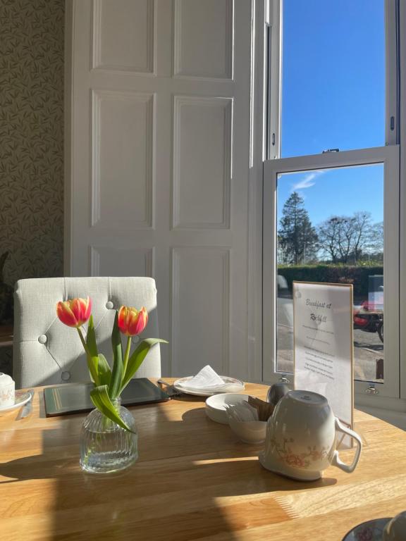 a wooden table with a vase of flowers on it at Rockhill Guest House in Moffat