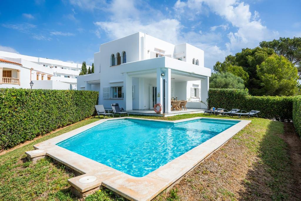 a villa with a swimming pool in front of a house at Villa Sa Caleta de Cala D'or in Santanyi
