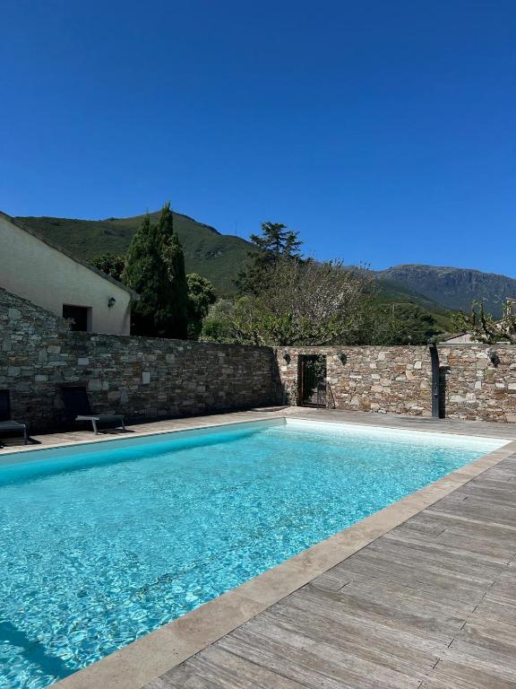 a swimming pool in front of a stone wall at Appartement en résidence d'exception avec piscine dans le cap corse in Sisco