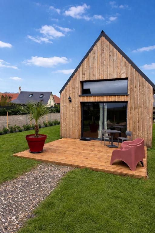 a small wooden house with a deck in a yard at Chalet in Paluel