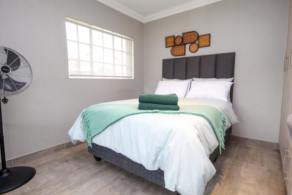 a bedroom with a large bed and a fan at Scheunberg 4 Modern 1 Bedroom Flat in Centurion