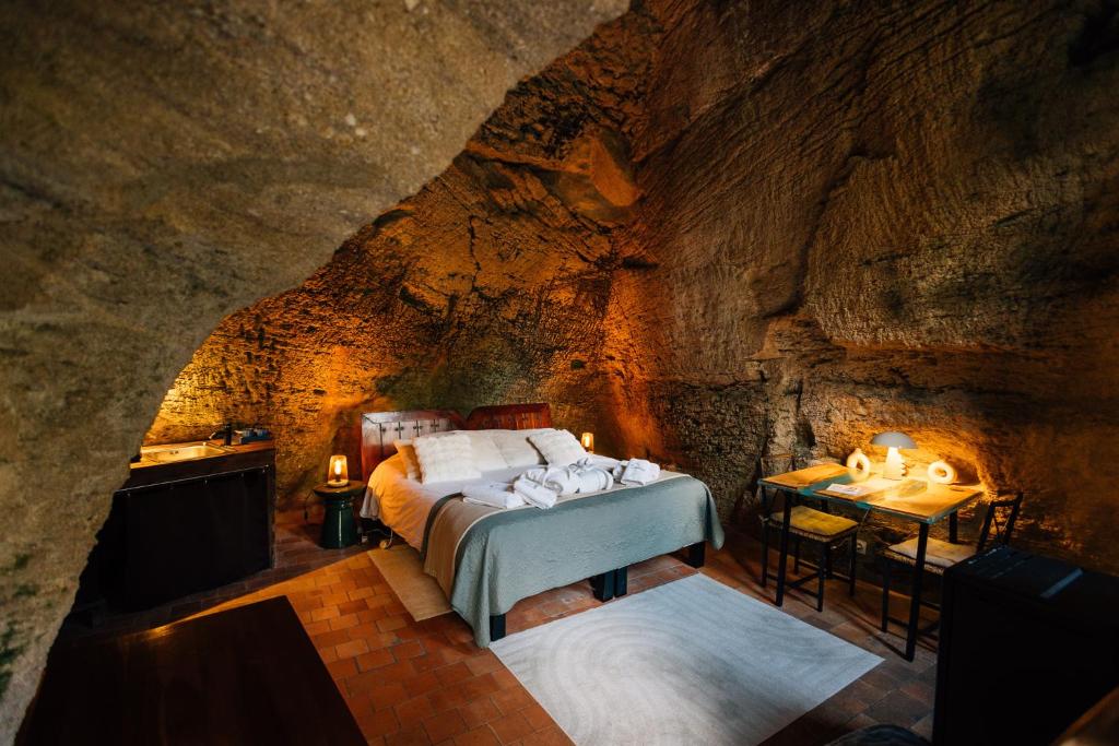 a bedroom in a cave with a bed and a table at La Voûte Etoilée in Doué-la-Fontaine