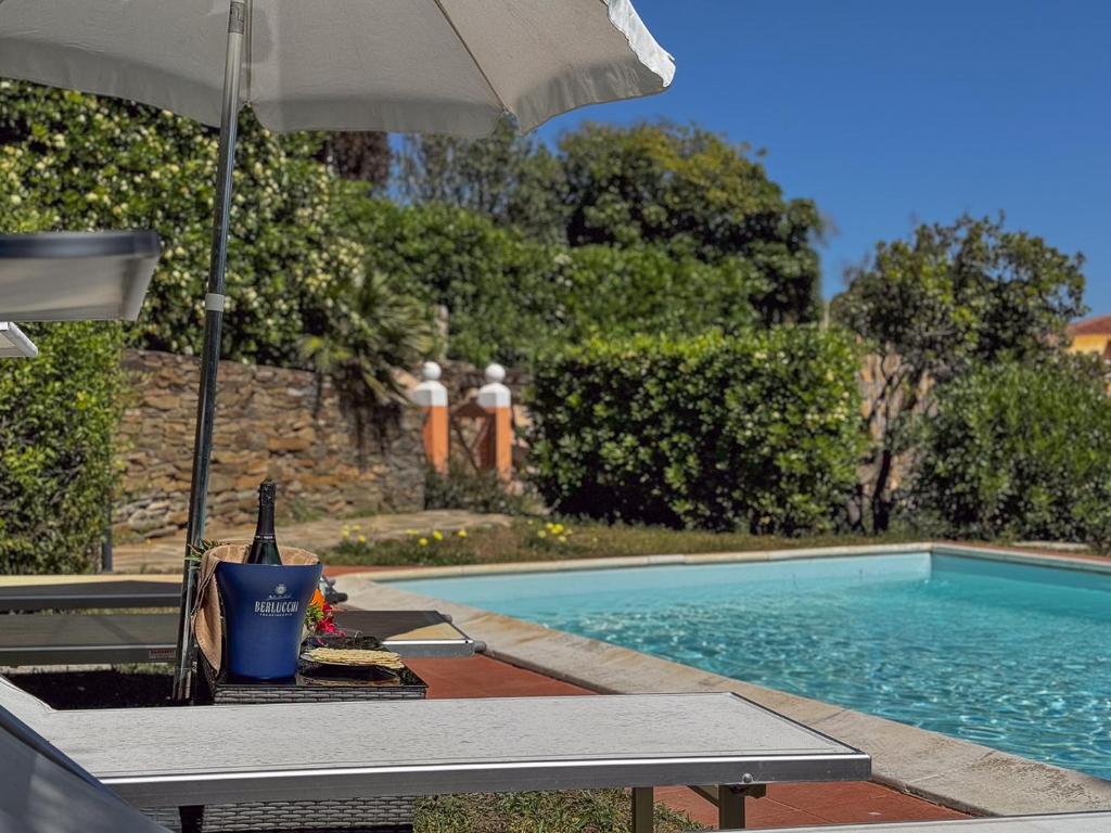 a swimming pool with an umbrella and a table with a drink at Villa Gilda - Private Pool by Host Hero in Stintino