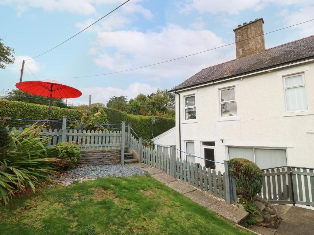 a house with a fence and an umbrella in the yard at 2 Argoed in Llanbedrog