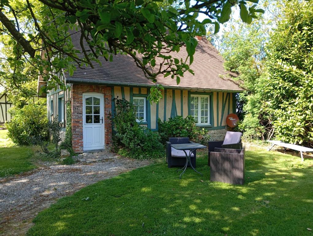 a house with a table and chairs in the yard at La Ferme aux Canards in Sassetot-le-Mauconduit