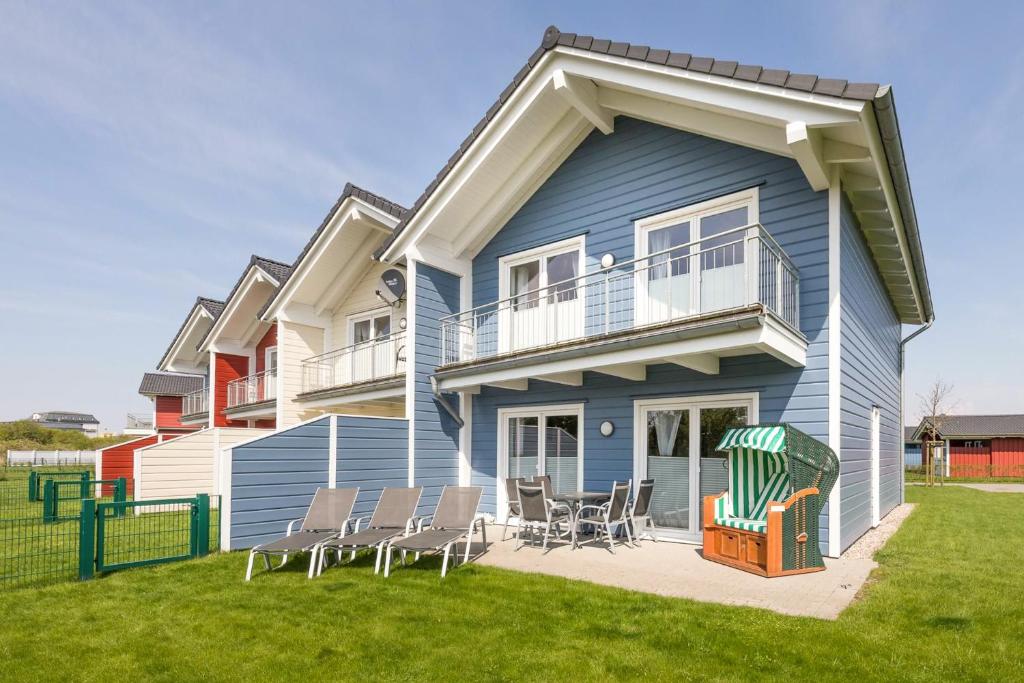a blue house with chairs on a lawn at Ferienhaus Basstölpel in Dagebüll