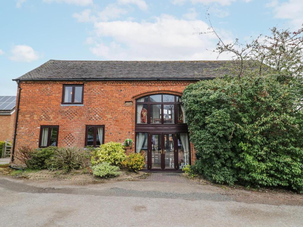 a brick house with a woman in the window at The Haybarn in Lichfield