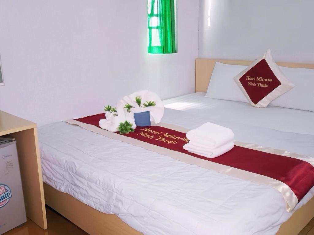 a bed with two pillows and a sign on it at Mimosa 6 Hotel - Phan Rang in Phan Rang–Tháp Chàm