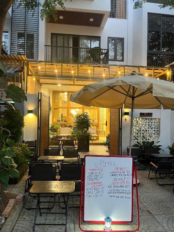 a restaurant with tables and an umbrella and a sign at Victoria home in Vĩnh Thái
