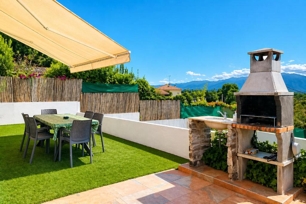 a backyard with a grill and a table and chairs at Ca la Nena Morena - Casa con piscina privada, jardín y vistas al Montseny in Vallgorguina